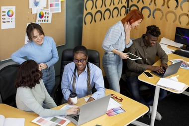 A diverse group of professionals collaborating on laptops in a modern office environment.